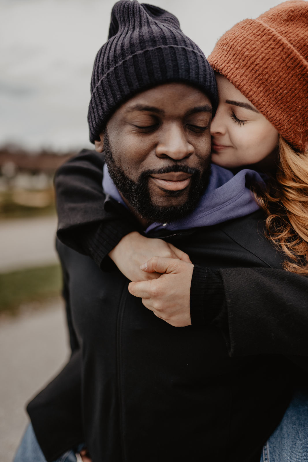 Ein Mann hält seine Verlobte Frau huckepack und sie kuscheln sich während dem Paar Fotoshooting ganz vertraut und nahe aneinander, die Gesichter liegen sanft beinander.