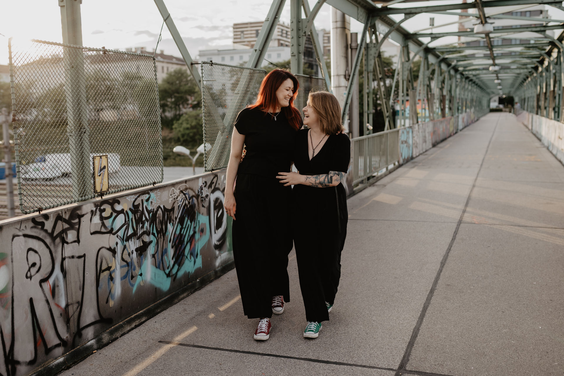 Ein lesbisches Paar geht auf einer Brücke spazieren und eine Fotografin hält diese Momente bei einem urbanem Paarshooting in Wien fest.